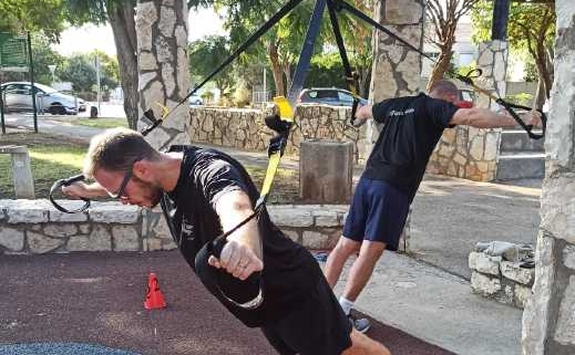 שני בחורים מבצעים תרגיל באימון פונקציונלי עם רצועות trx