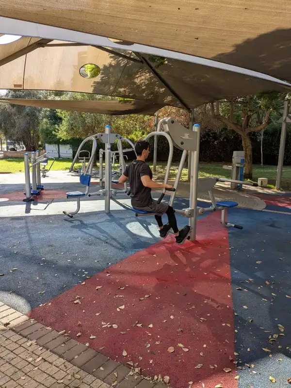 בחולצה שחורה ומבצע תרגילי התנגדות בפארק
