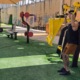 מה ההבדל בין פעילות אירובית לאנאירובית: למה כל אחת מתאימה ואיך לשלב ביניהן בחור בגופיה שחורה מבצע תרגיל לחיצת כתפיים עם מכשיר בתוך גינה עם מכשירי כושר